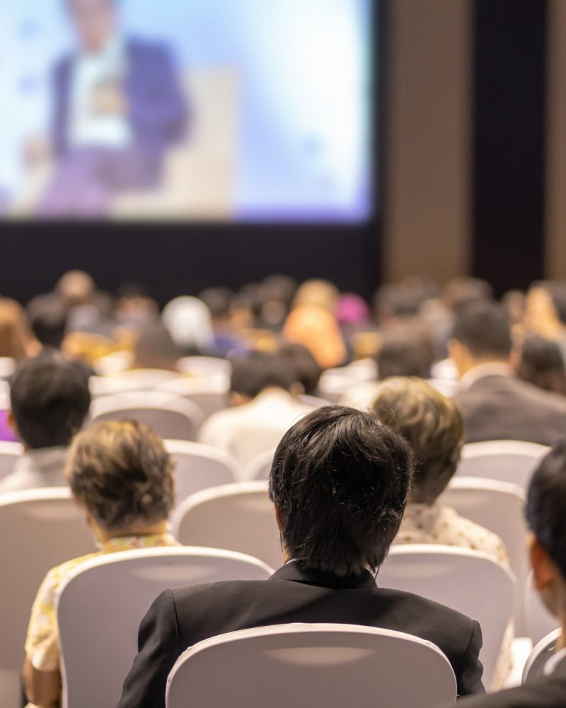 Rear view of Audience listening Speakers on the stage in the conference hall or seminar meeting